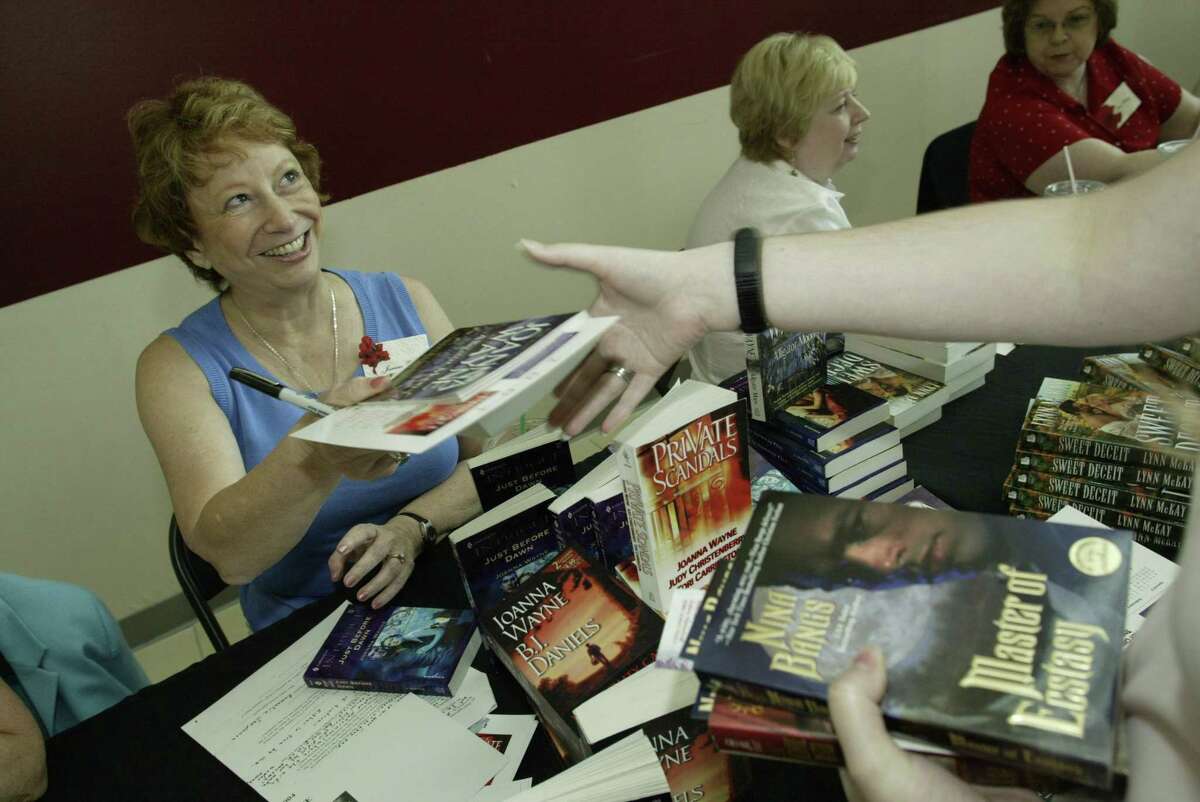 Houston-area romance writer Joanna Wayne hands out an autographed copy of her book during a Romance Writers of America event.