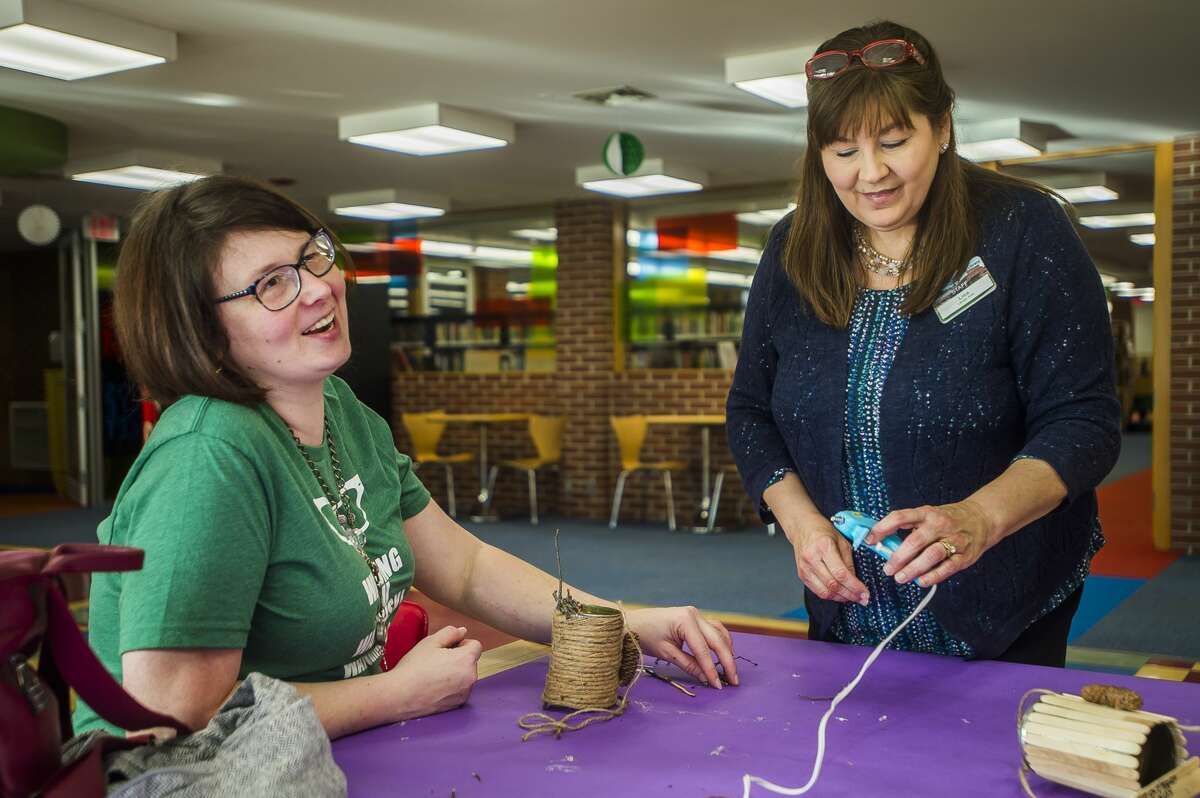 Alisha Hasselhuhn, left, laughs while constructing a bird feeder while library employee Lisa Novak, right, assists her during a crafting class Wednesday, Jan. 8, 2020 at Grace A. Dow Memorial Library. (Katy Kildee/kkildee@mdn.net)