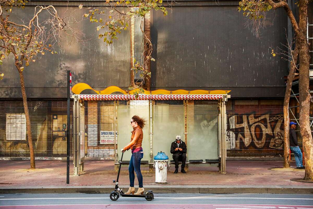 A woman rides a scooter down Market Street in San Francisco, California, on Monday, Oct. 7, 2019.