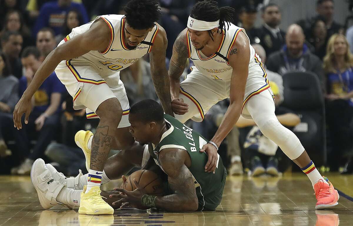 Milwaukee Bucks' Eric Bledsoe, center, keeps the ball from Golden State Warriors' Jacob Evans left, and Damion Lee, right, during the first half of an NBA basketball game Wednesday, Jan. 8, 2020, in San Francisco. (AP Photo/Ben Margot)