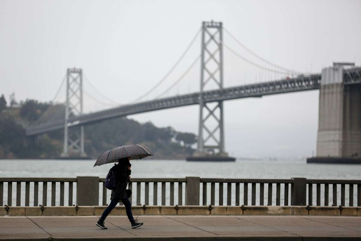 Pedestrians cover up from the rain on Wednesday, May 15, 2019 in San Francisco, Calif.