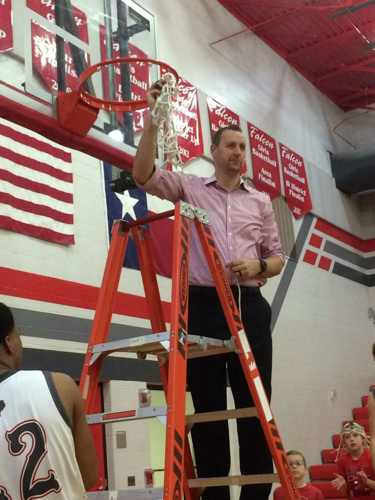Coach Scott Barrett proudly holds the net after the team finishes cutting it down after the Hargrave boys basketball team completed an undefeated district championship in the 2016-2017 season.