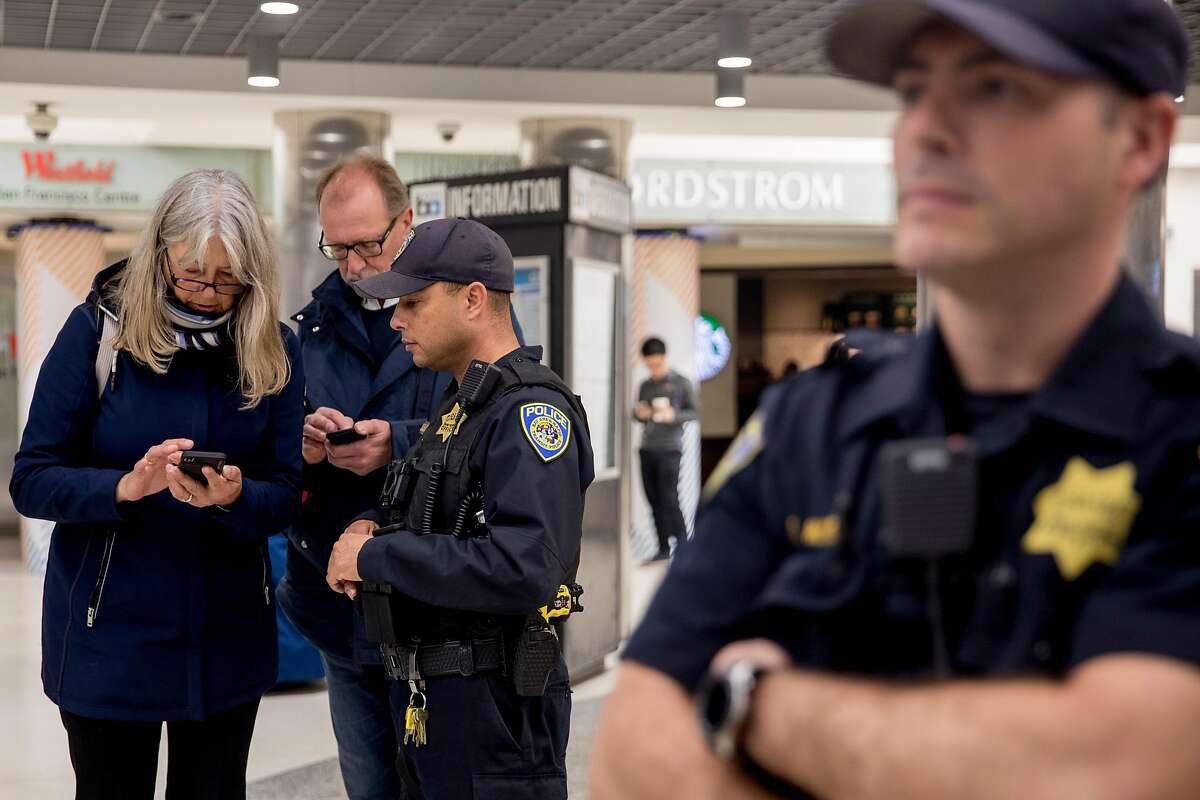 Bart Police Officer C. Dazhan (left) assists passengers with directions while patrolling Powell Street Bart Station in San Francisco, Calif. Thursday, Jan. 9, 2020.