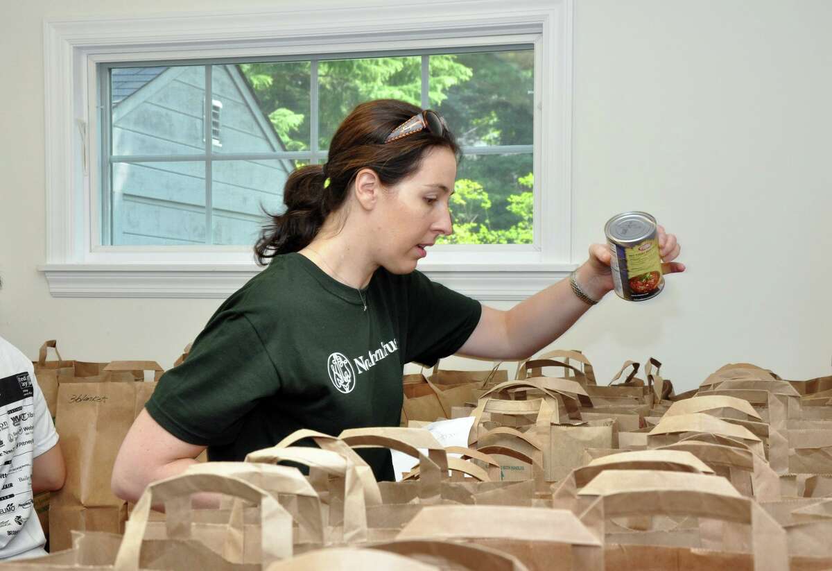 A United Way volunteer adds a can of beans to a grocery bag at the Person-to-Person pantry.