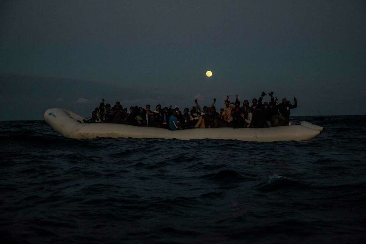 Migrants and refugees from different African nationalities react on an overcrowded wooden boat, as aid workers of the Spanish NGO Open Arms approach them in the Mediterranean Sea, international waters, off the Libyan coast, in January 2020. Texas Gov. Greg Abbott said Friday that the state will stop the re-settlement of new refugees, becoming the first state known to do so under a recent Trump administration order.
