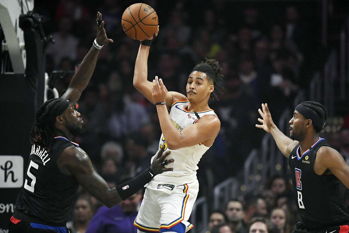 Golden State Warriors guard Jordan Poole, center, passes the ball as Los Angeles Clippers forward Montrezl Harrell, left, and forward Maurice Harkless defend during the first half of an NBA basketball game Friday, Jan. 10, 2020, in Los Angeles. (AP Photo/Mark J. Terrill)