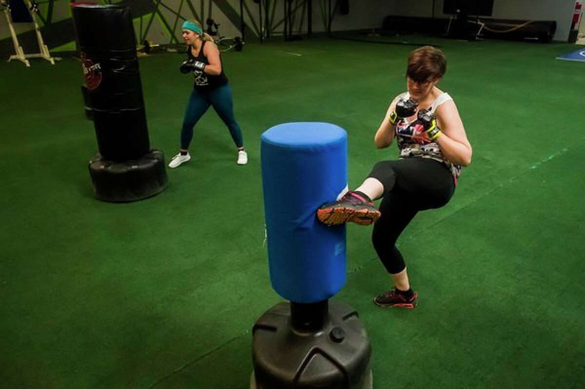 Amanda Austin of Essexville, left, and Adrienne Gibson of Hope, right, kick punching bags during a kickboxing class Thursday at Edge Fitness and Training Headquarters in Midland. (Katy Kildee/kkildee@mdn.net)