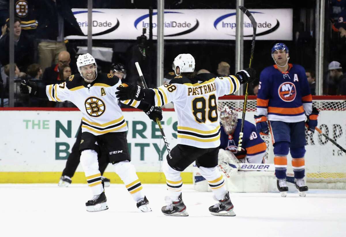 NEW YORK, NEW YORK - JANUARY 11: Patrice Bergeron #37 of the Boston Bruins (L) celebrates his game winning power-play goal at 2:33 of overtime against the New York Islanders and is joined by David Pastrnak #88 (R) at the Barclays Center on January 11, 2020 in the Brooklyn borough of New York City. (Photo by Bruce Bennett/Getty Images)