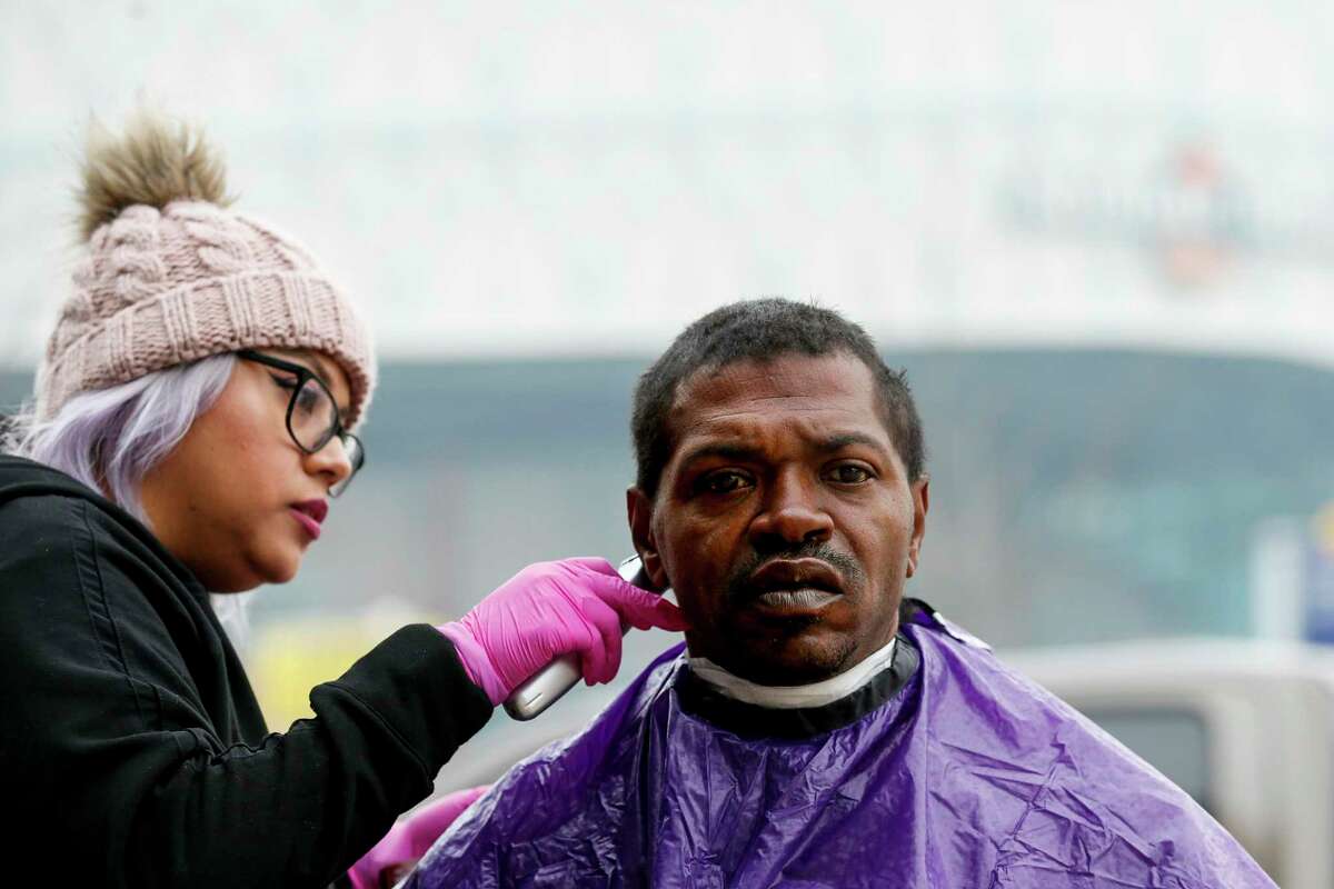 Marel Valencia, with Hair Angels, cuts Pascal Herbert's hair during the HOPE for Houston day of outreach and donation drop off in downtown Houston near the Interstate 69 overpass.