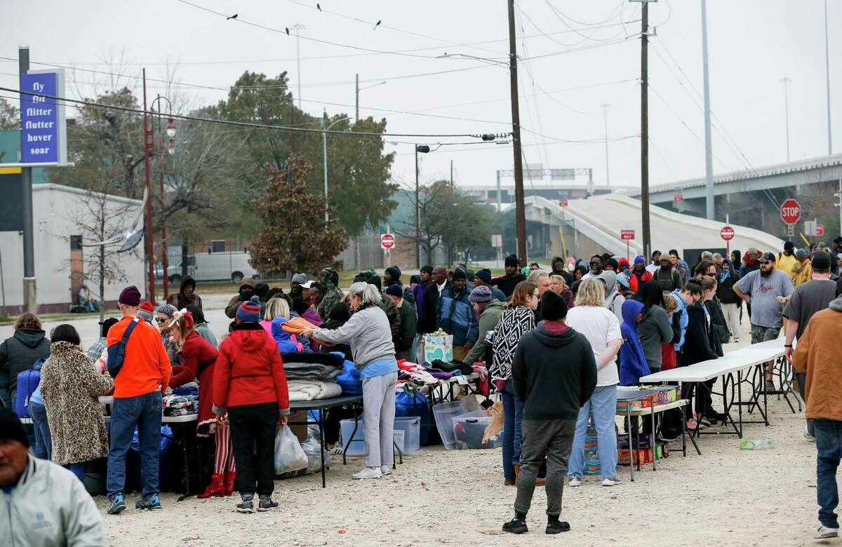 Homeless people wait in line to receive blankets, clothing, and hygiene items.
