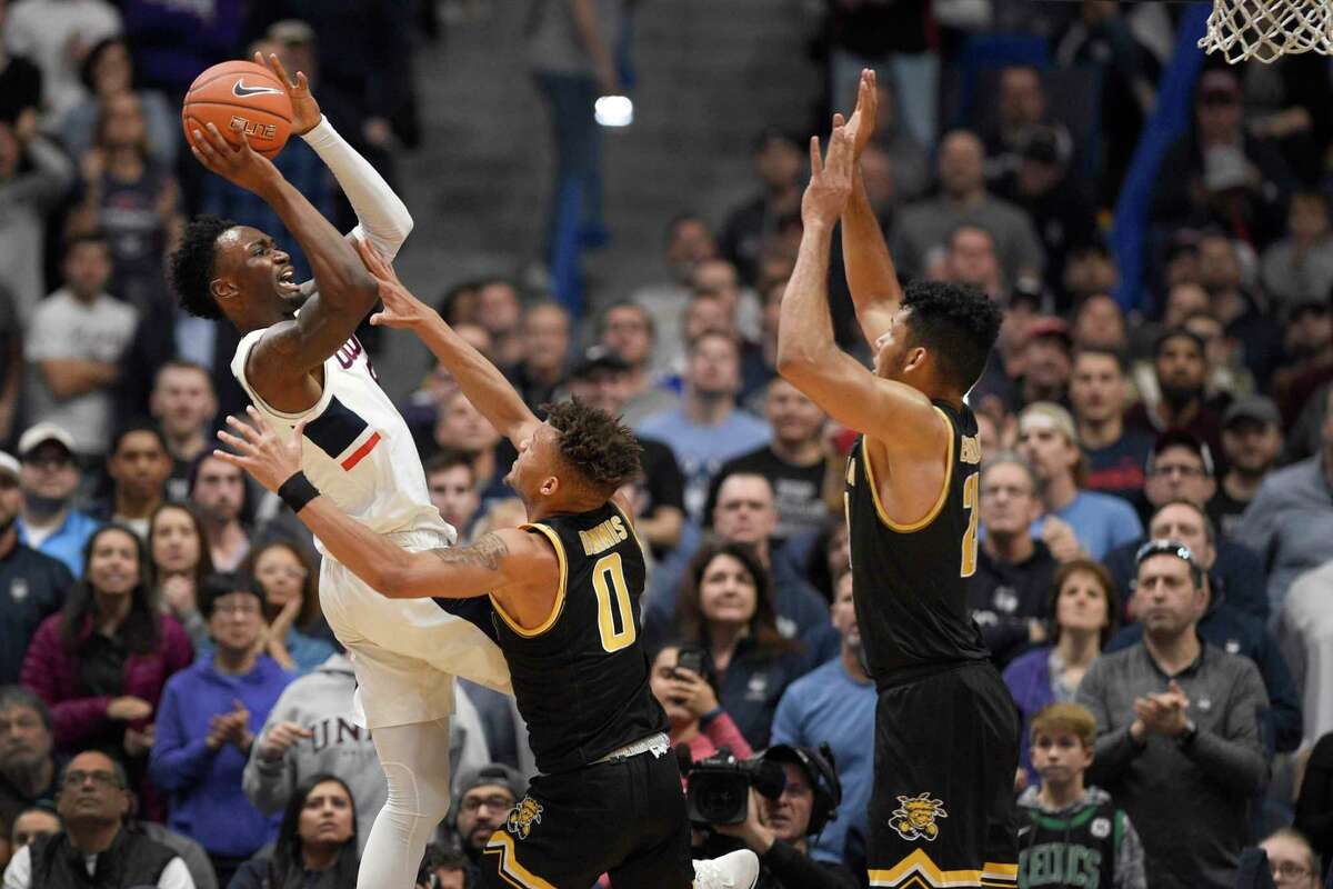 Connecticut's Sidney Wilson, left, shoots over Wichita State's Dexter Dennis, center, and Wichita State's Jaime Echenique, right, in the second half of an NCAA college basketball game, Sunday, Jan. 12, 2020, in Hartford, Conn. (AP Photo/Jessica Hill)