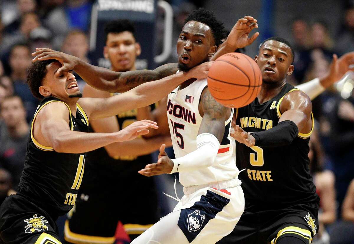 Connecticut's Sidney Wilson, center, fights for the ball between Wichita State's Noah Fernandes, left, and Trey Wade, right, in the first half of an NCAA college basketball game, Sunday, Jan. 12, 2020, in Hartford, Conn. (AP Photo/Jessica Hill)