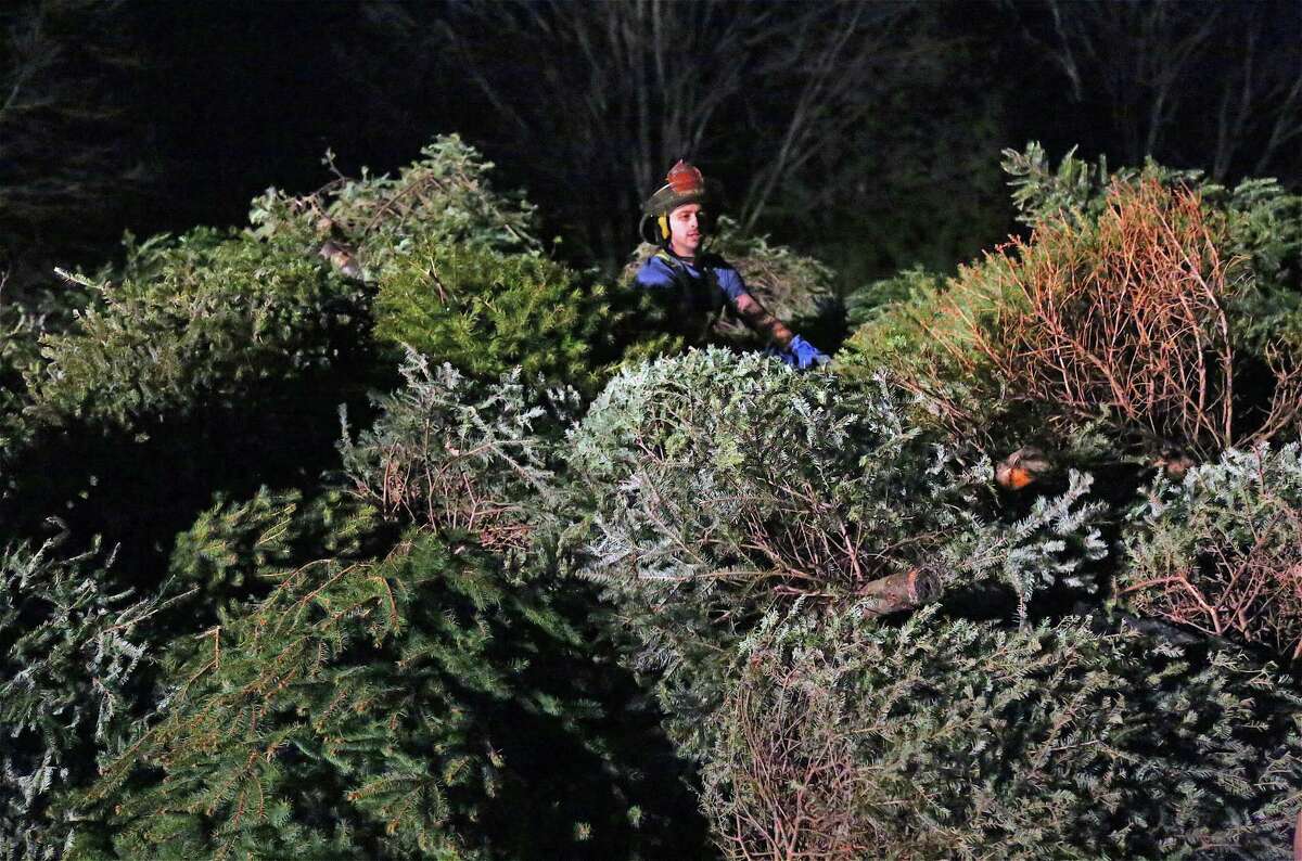 Firefighter Colin Carroll climbs atop the enormous tree pile to get things straightened out at the annual Epiphany Bonfire at Emmanuel Episcopal Church on Jan. 11, 2020, in Weston.
