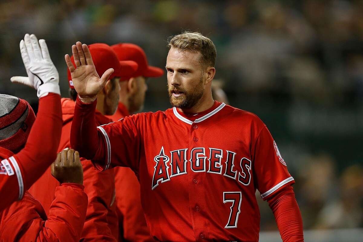 OAKLAND, CA - MARCH 30: Zack Cozart #7 of the Los Angeles Angels of Anaheim celebrates with teammates after scoring on a single off the bat of Andrelton Simmons in the top of the eighth inning against the Oakland Athletics at Oakland-Alameda County Colise