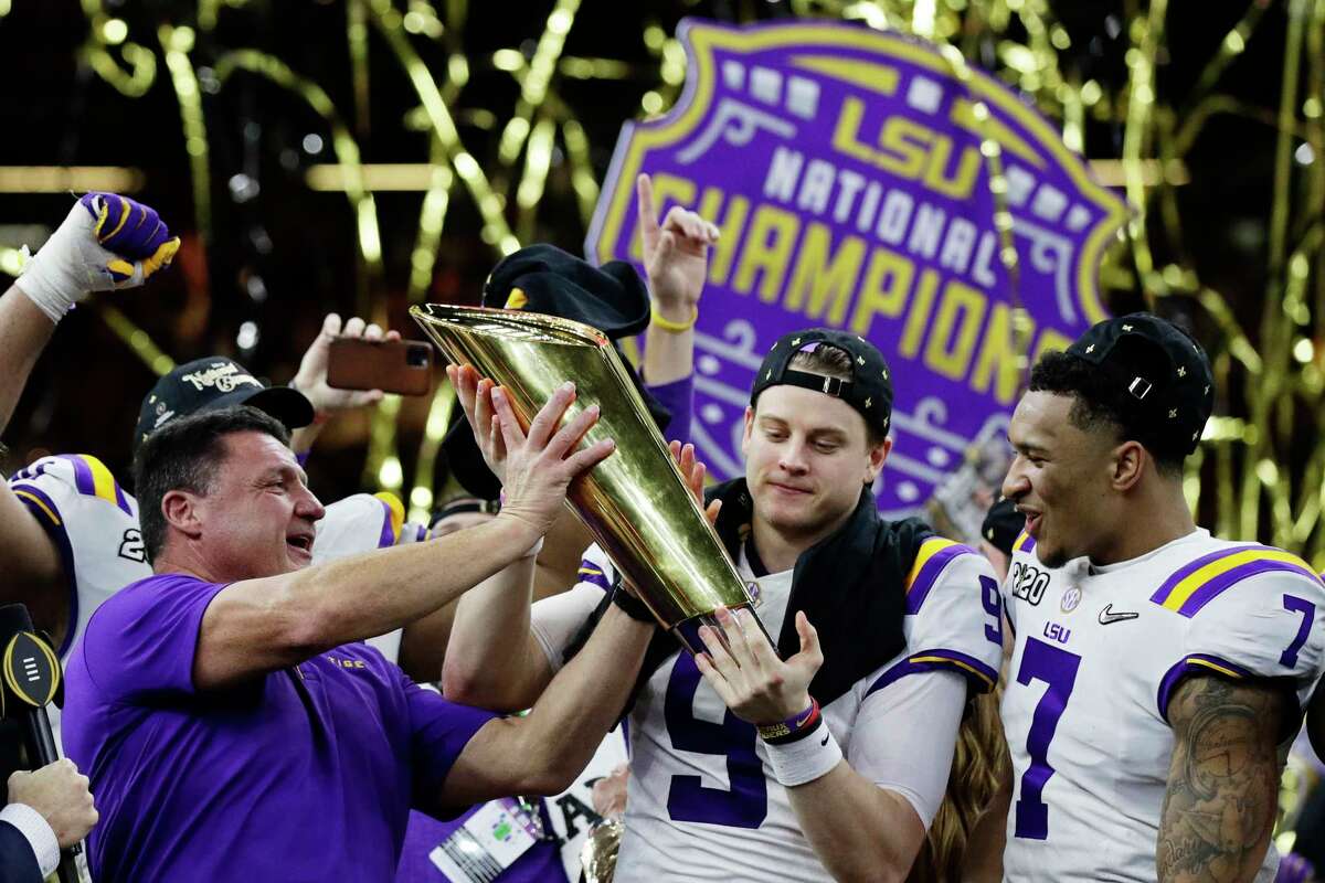 LSU head coach Ed Orgeron, left, and quarterback Joe Burrow, center, hold the trophy beside safety Grant Delpit after a NCAA College Football Playoff national championship game against Clemson, Monday, Jan. 13, 2020, in New Orleans. LSU won 42-25. (AP Photo/Sue Ogrocki)