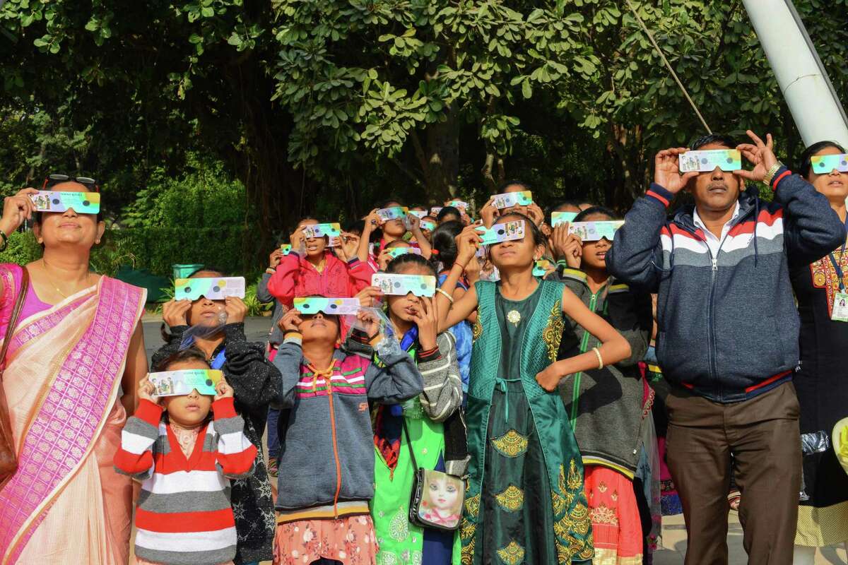 TOPSHOT - Students and teachers use solar filter glasses to look at the solar eclipse at Gujarat Science City on the outskirts of Ahmedabad on December 26, 2019. (Photo by SAM PANTHAKY / AFP) (Photo by SAM PANTHAKY/AFP via Getty Images)