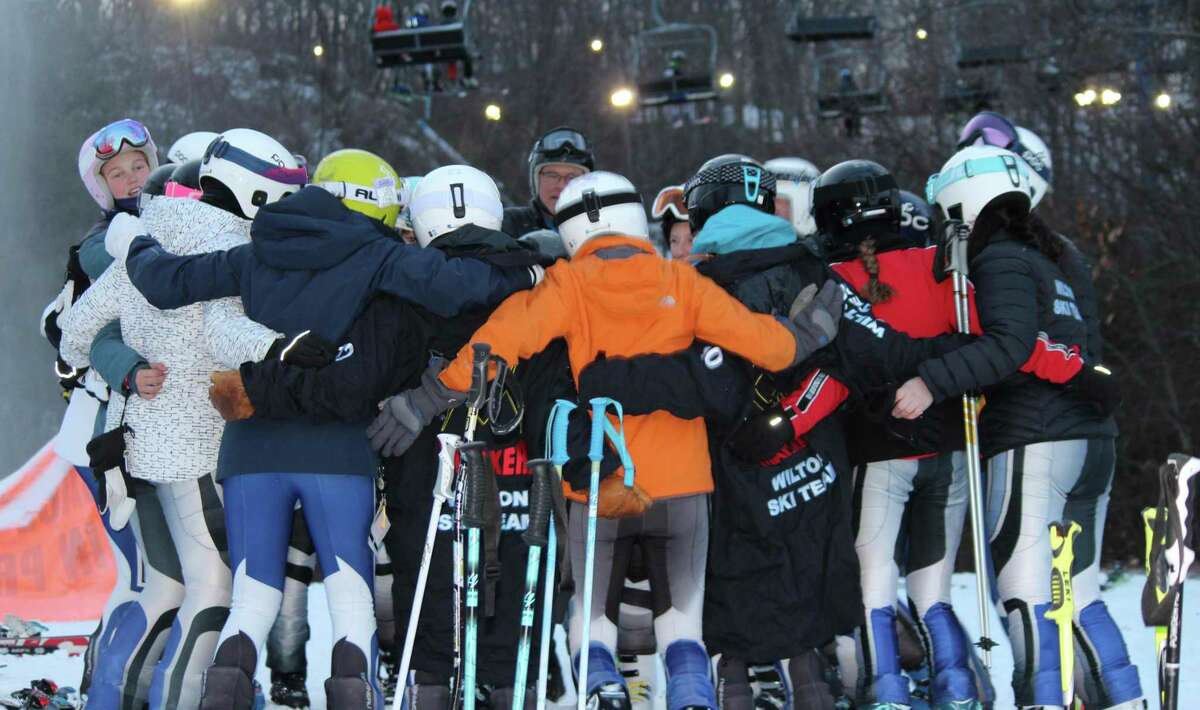 The Wilton girls ski team gathers around coach Bill Howard at last week's season-opening race.