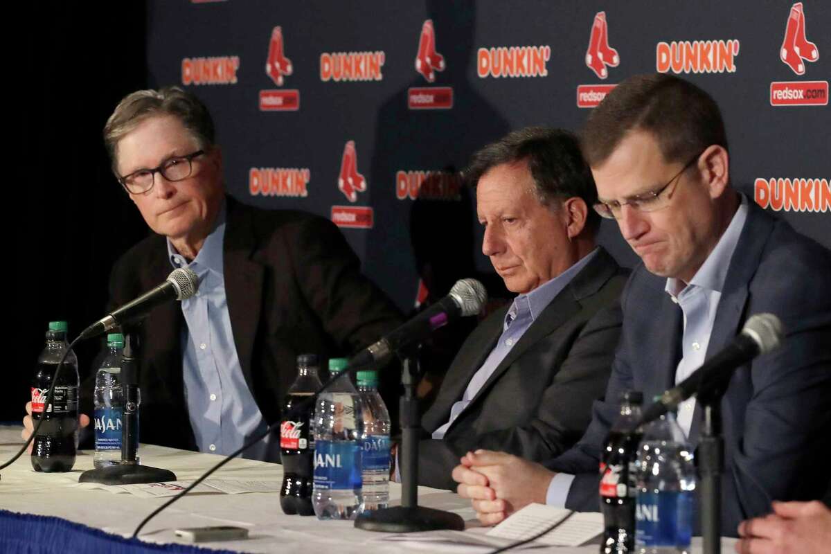 From left, Boston Red Sox owner John Henry, chairman Tom Werner and CEO Sam Kennedy react during a news conference at Fenway Park, Wednesday, Jan. 15, 2020, in Boston. The Boston Red Sox have parted ways with manager Alex Cora, with the move coming one day after baseball Commissioner Rob Manfred named him as a ringleader with Houston in the sport's sign-stealing scandal. (AP Photo/Elise Amendola)