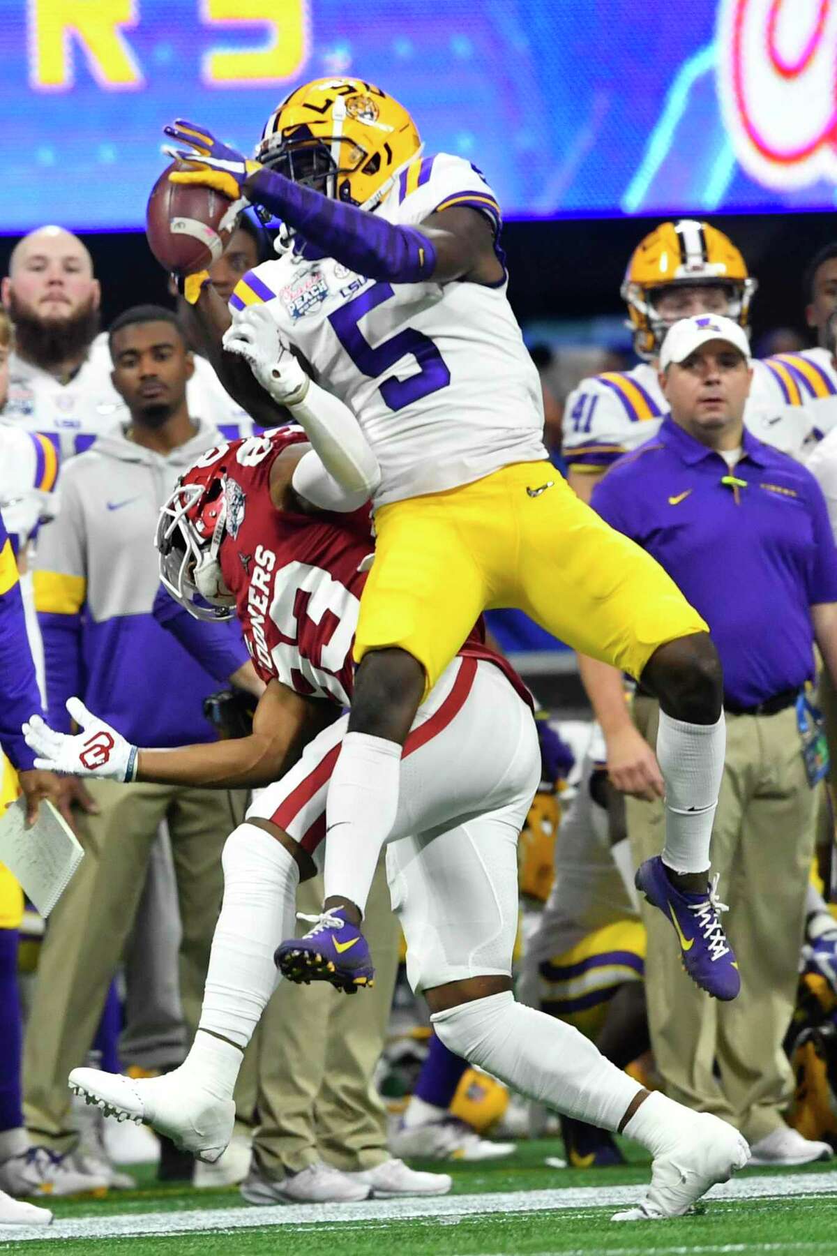 LSU cornerback Kary Vincent Jr. (5) picks off a ball intended for Oklahoma wide receiver Nick Basquine (83) during the first half of the Peach Bowl NCAA semifinal college football playoff game, Saturday, Dec. 28, 2019, in Atlanta. (AP Photo/John Amis)