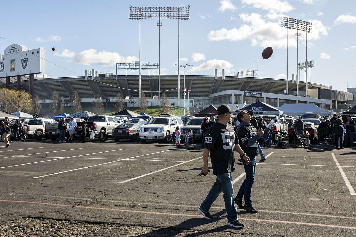 Armando Ochoa and his son Aaron Ochoa, 13, play with the football outside the Oakland Coliseum before the NFL game between the Oakland Raiders and Jacksonville Jaguars on Sunday, Dec. 15, 2019, in Oakland, Calif.