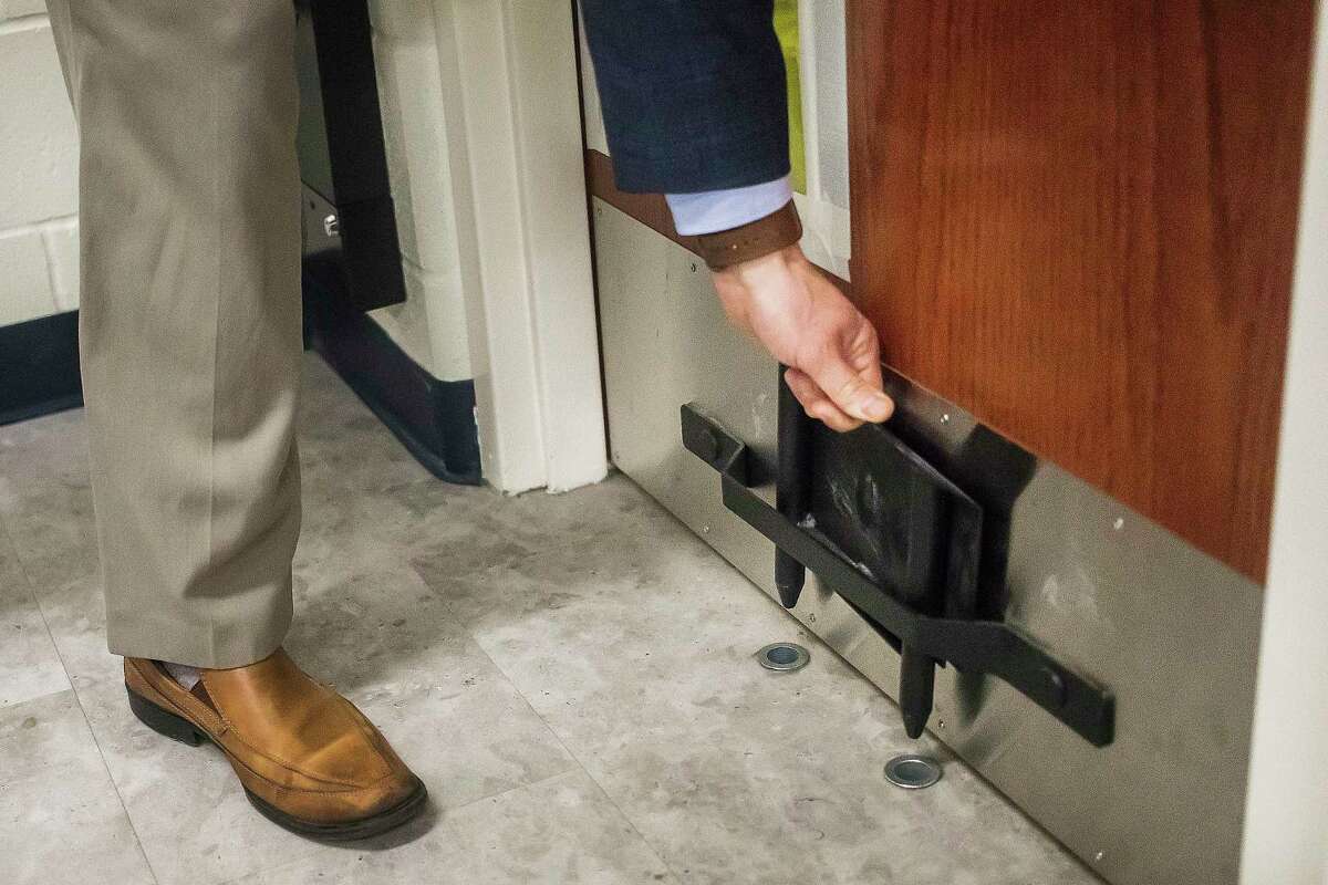 Craig Carmoney, superintendent for Meridian Public School District, demonstrates how a metal security boot is used on a classroom door Tuesday at Meridian Elementary. (Katy Kildee/kkildee@mdn.net)