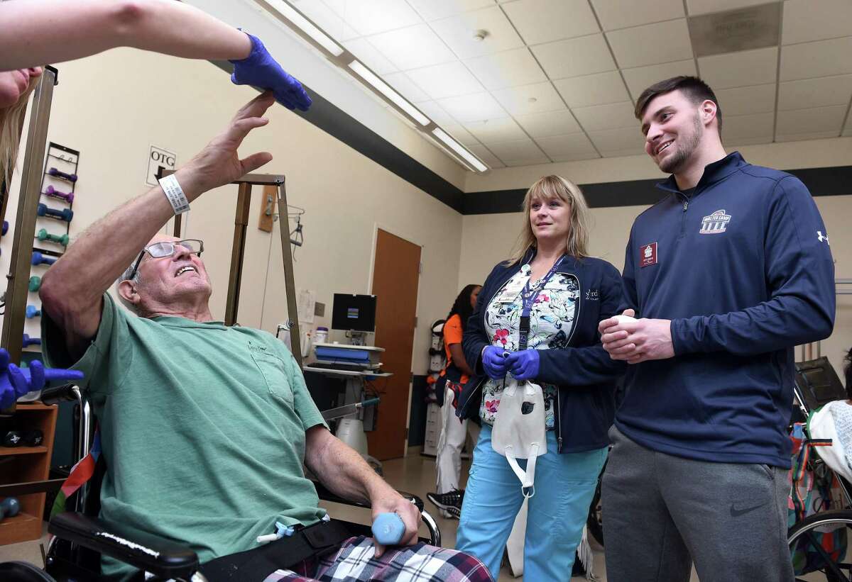 John Acerbi (left) of Litchfield meets with 2019 Walter Camp Football Foundation All-American Keith Duncan (right) of Iowa while doing exercises with occupational therapist Katie Zimmerli (far left) at the Gaylord Hospital inpatient therapy room in Wallingford on January 17, 2020. In the background is rehabilitation aid Dawn Peck.