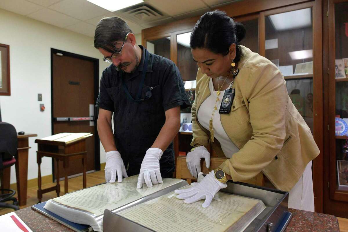 Spanish archivist David Carlson, left, and Bexar County Clerk Lucy Adame-Clark look over documents in the Bexar County Spanish Archives Department on Sept. 26, 2019.