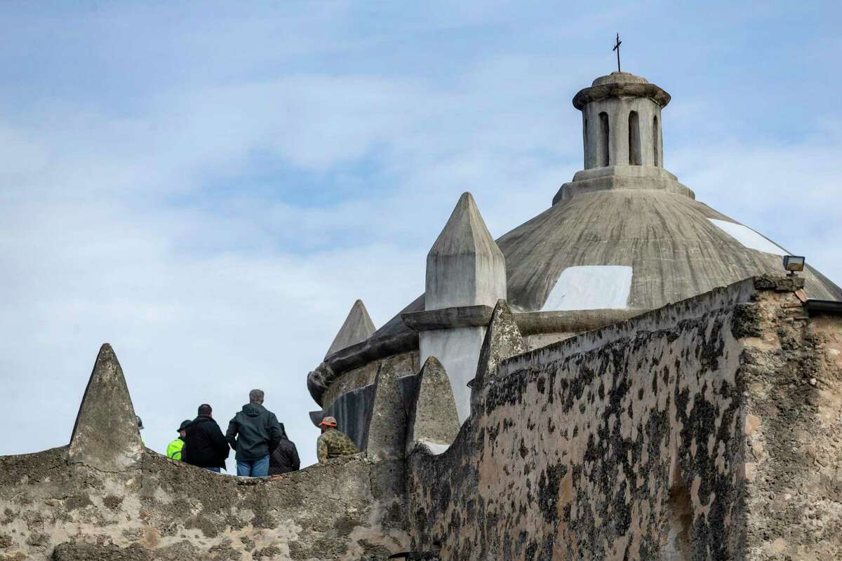 People with the architectural and construction firms overseeing the renovation of Mission Concepcion's dome stand Tuesday, Jan. 21, 202, on the building's roof while they examine the structure.