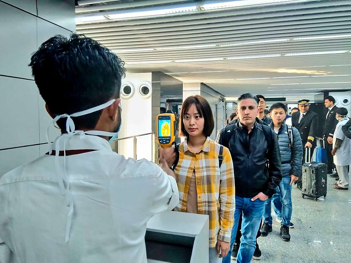 In this handout photograph taken and released by the Ministry of Civil Aviation (MoCA) on January 21, 2020, a man (L) uses a thermographic camera to screen the head of people at Netaji Subhash Chandra Bose International Airport in Kolkata, following the Ministry of Health and Family Welfare's advisory to screen passengers arriving in India from China and Hong Kong regarding the novel coronavirus (nCoV) issue. - Asian countries on January 21 ramped up measures to block the spread of a new virus as the death toll in China rose to six and the number of cases jumped to almost 300, raising concerns in the middle of a major holiday travel rush. (Photo by Handout / Ministry of Civil Aviation (MoCA) / AFP) / RESTRICTED TO EDITORIAL USE - MANDATORY CREDIT "AFP PHOTO / Ministry of Civil Aviation (MoCA)" - NO MARKETING - NO ADVERTISING CAMPAIGNS - DISTRIBUTED AS A SERVICE TO CLIENTS (Photo by HANDOUT/Ministry of Civil Aviation (MoCA/AFP via Getty Images)