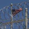 FILE - In this April 17, 2019 file photo reviewed by U.S. military officials, a U.S. flag flies inside the razor wire of the Camp VI detention facility, Wednesday, April 17, 2019, in Guantanamo Bay Naval Base, Cuba. (AP Photo/Alex Brandon)