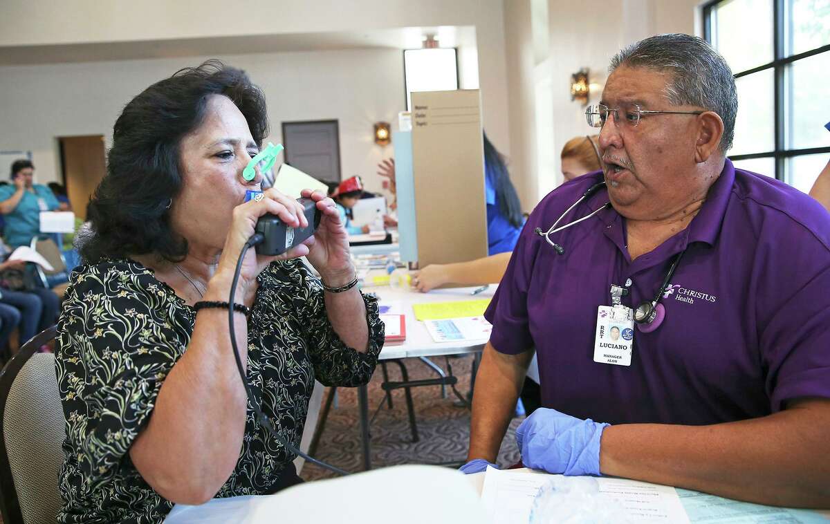 Luciano Valdez, a respiratory therapist from Christus Santa Rosa, coaches Lydia Mireles as she draws a big breath to test her capacity during a health fair in 2015.