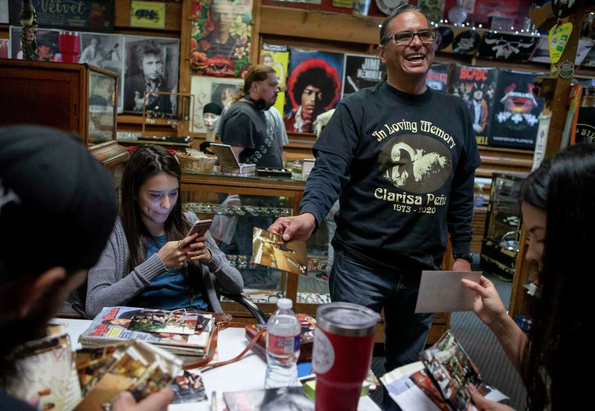Roman Cuellar laughs as he looks over old photos at Flip Side Record Parlor with his nieces Olivia Peña, left, and Jessica Erevia, right. The South Side store has an uncertain future following the recent death of its owner Clarisa Peña, who was Olivia and Jessica’s mother and Cuellar’s sister.