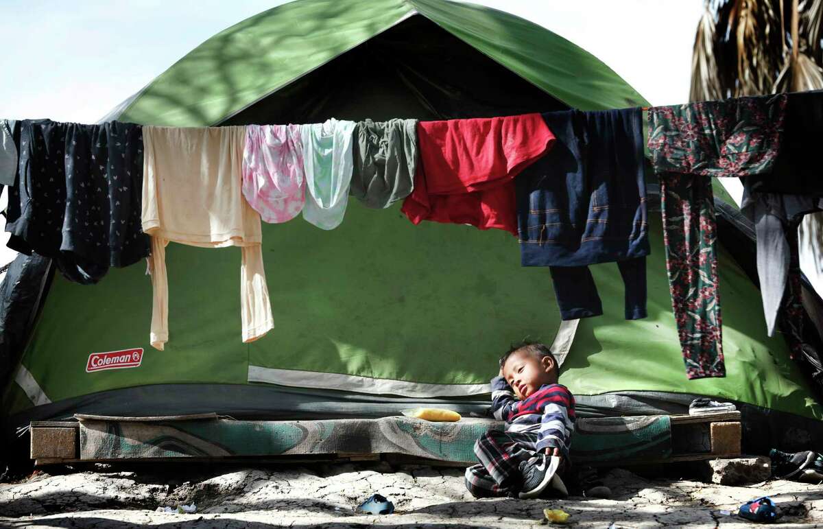 A young migrant boy rests in front of his family's tent in the refugee camp in Matamoros, Mexico.
