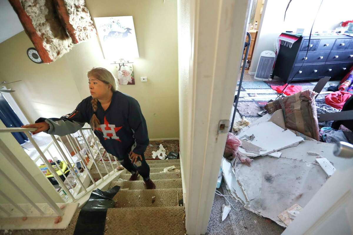 Maria Hernandez climbs her stairwell as she and her family worked to move their belongings out as they sifted through their damaged home in the Bridgeland Lane area of Houston, Sunday, Jan. 26, 2020, after the Watson Grinding Manufacturing explosion early Friday morning. Her ceiling, right, collapsed even further after overnight rains.