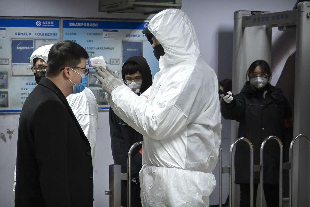 A worker wearing a hazardous materials suit takes the temperature of a passenger at the entrance to a subway station in Beijing, Sunday, Jan. 26, 2020. The new virus accelerated its spread in China, and the U.S. Consulate in the epicenter of the outbreak, the central city of Wuhan, announced Sunday it will evacuate its personnel and some private citizens aboard a charter flight. (AP Photo/Mark Schiefelbein)