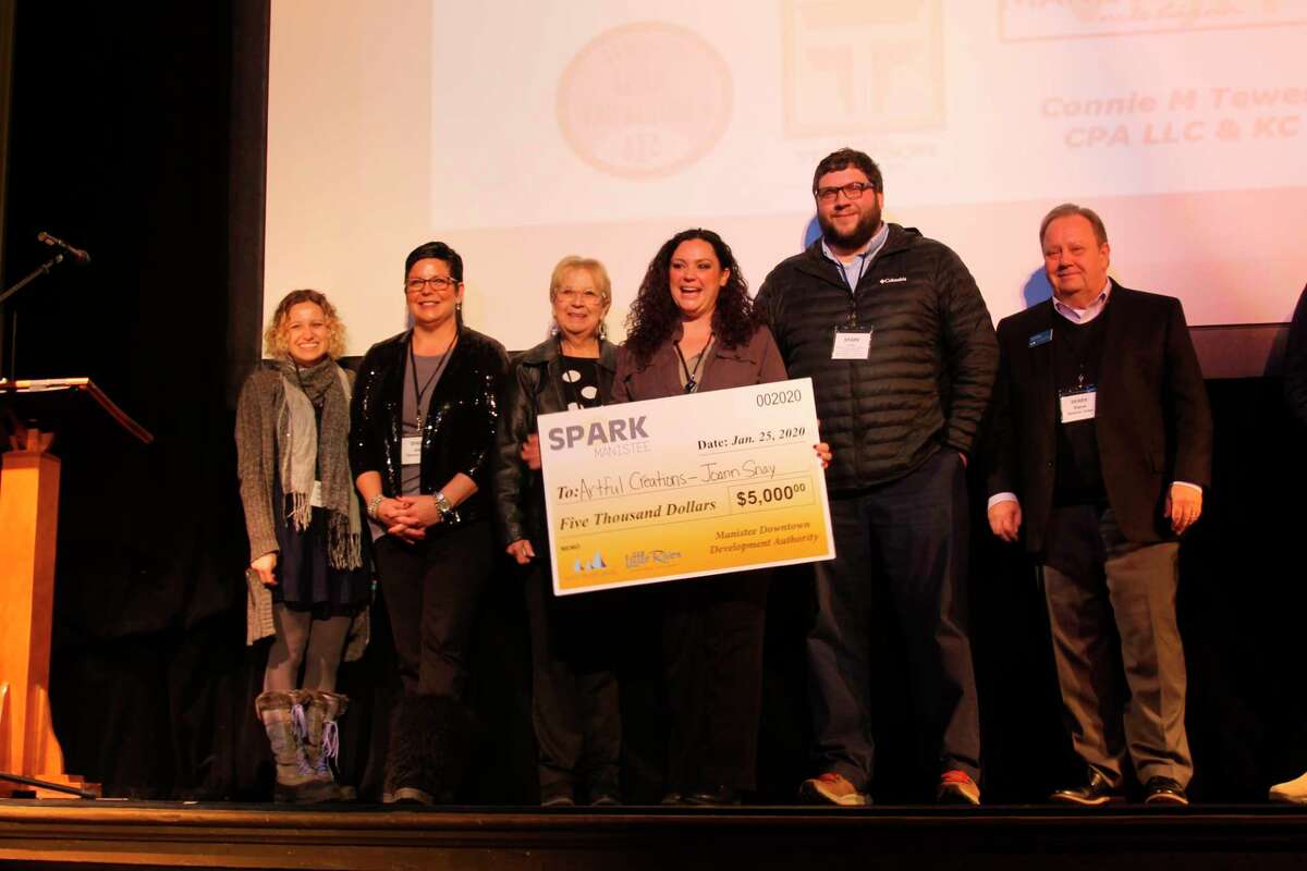 Judges and Manistee DDA executive director Caitlyn Berard (far left) stand with Spark Manistee winner Joann Snay (center) on Saturday at the Ramsdell Regional Center for the Arts. Snay, along with four other local entrepreneurs, gave a five-minute pitch for their business before the judges announced the winner. (Michelle Graves/News Advocate)