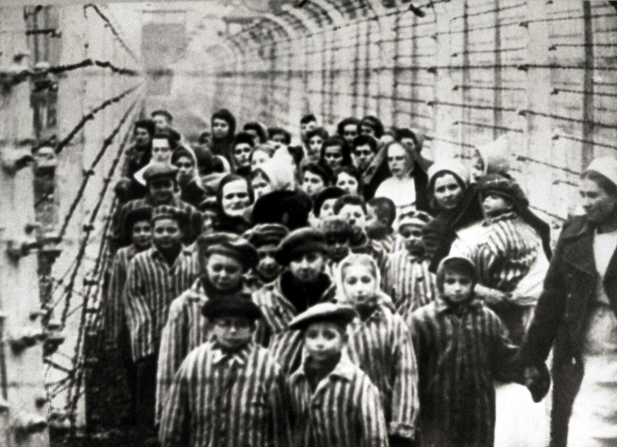Jewish children, survivors of Auschwitz, with a nurse behind a barbed wire fence, Poland, February 1945. Photo taken by a Russian photographer during the making of a film about the liberation of the camp.
