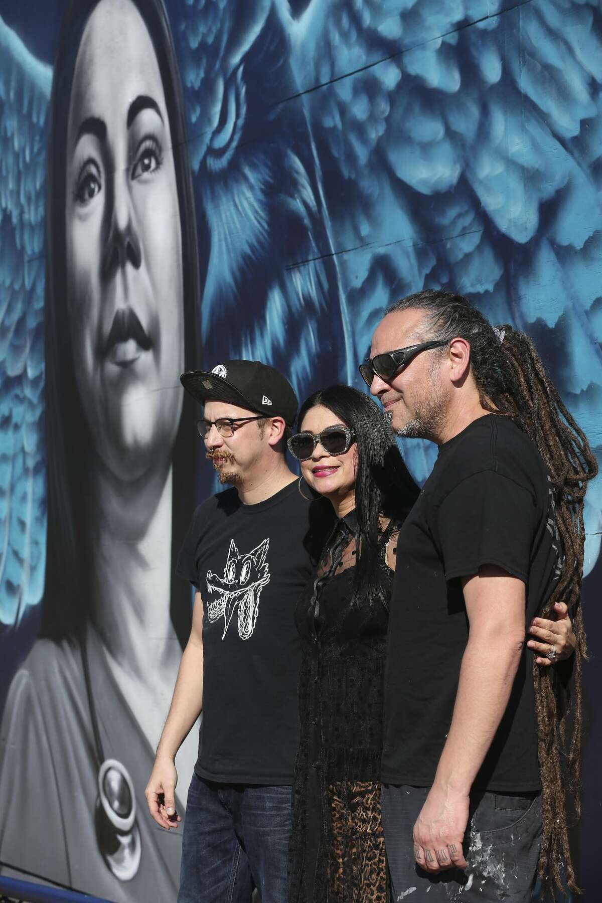 Jacqueline Becerra, a local nursing director, pastor and philanthropist, poses with Los Otros art duo Shek Vega, left, and Nik Soupe as her portrait in a mural is unveiled on the side of Botello Food Store in the cityâs Westside, Sunday, Jan. 26, 2020. The with a mural is located in the underserved area of San Antonio where Becerra grew up. The mural â?“ painted by local street art duo, Los Otros â?“ is intended to inspire others in similar circumstances to reach their full potential. It was commissioned as part of Western Governors University's national "Role Model Murals" project. On the left is her husband Pastor Henry Becerra.