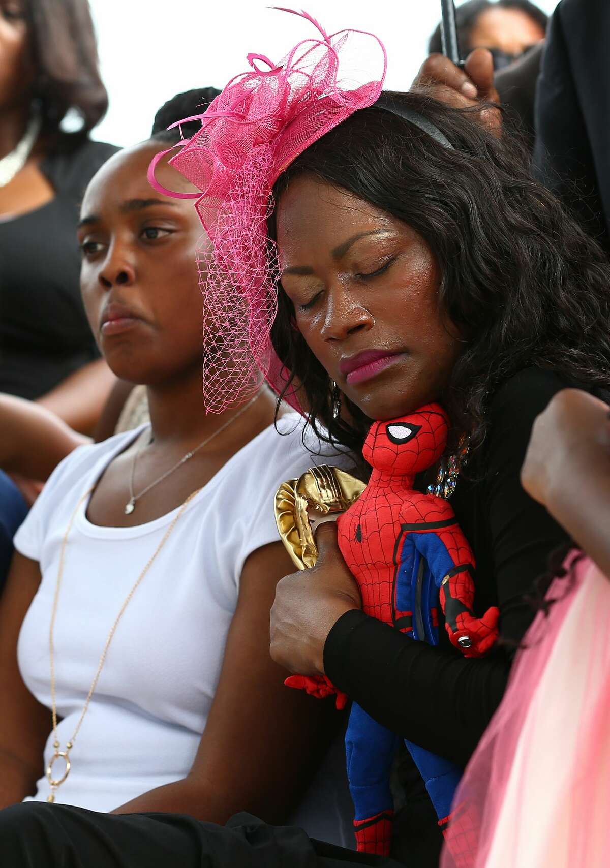 Roxane Freeman, center, holds tight her daughter's ballerina shoes, and her son's Sider-Man toy during the their burial at Paradise South Cemetery Saturday, July 29, 2017, in Houston.