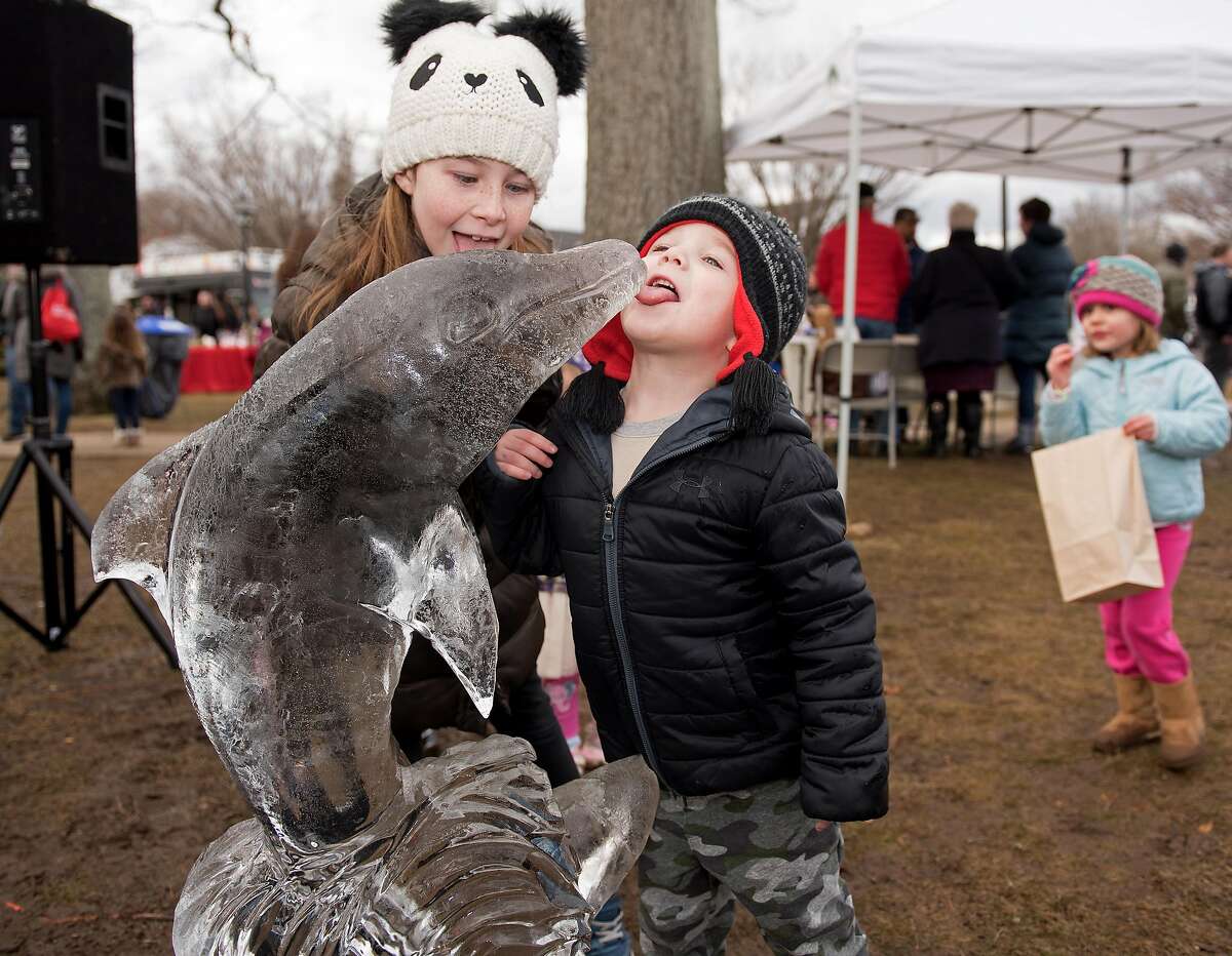 7-year-old Emma Nicoletti and brother, Jack, 4, pose with a dolphin ice sculpture at the third Annual Winter Carnival in Wilton, Conn. on Sunday, Jan. 26, 2020.