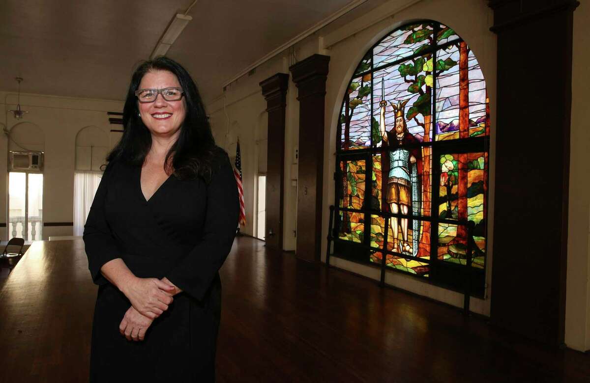 Lori Todd of the San Antonio Hermann Sons Home Association stands near a stained-glass window of Hermann the Cherusker, the Germanic leader who fought against the Roman Empire that prevented the Romanization of the German people. The window was created by San Antonio artist Helen Slimp in 1911 and was restored as part of recent revitalization efforts at the Hermann Sons building.