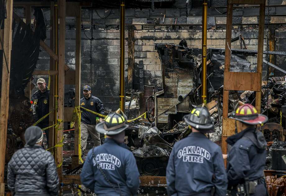 AFT police officials inspect the Ghost Ship warehouse from inside as Oakland firefighters investigate outside on Saturday, Dec. 10, 2016 in Oakland, Calif. 36 people were killed when a fire broke out on Dec. 2 at the Ghost Ship warehouse on 31st Avenue and International Boulevard in Oakland's Fruitvale neighborhood. As many as 100 people were inside attending a music performance. The blaze is now the deadliest structure fire in California since the 1906 earthquake and fire. Officials said the cause of ignition is still unknown and the building had no evidence of fire sprinklers. Photo: Santiago Mejia / The Chronicle