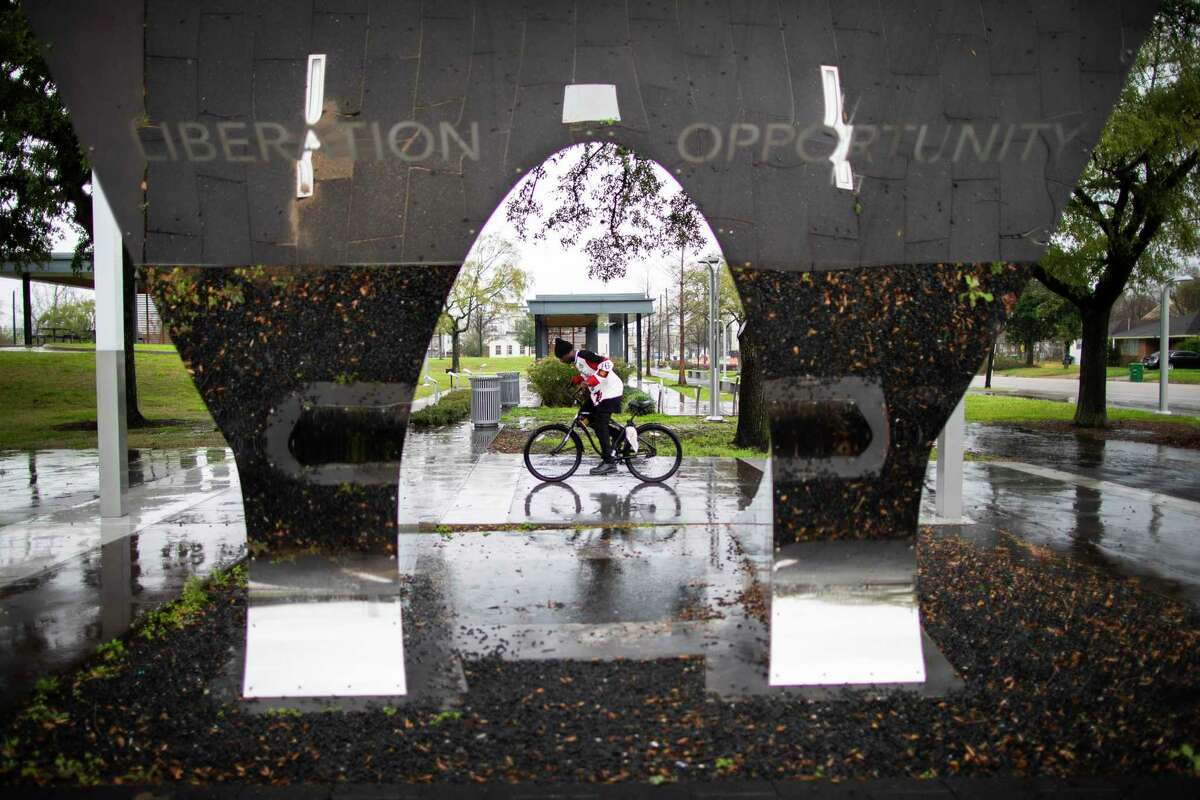 A person riding a bike is framed by a sculpture that stands at the Hutchins Street entrance of the Emancipation Park on Tuesday, Jan. 28, 2020, in Houston.