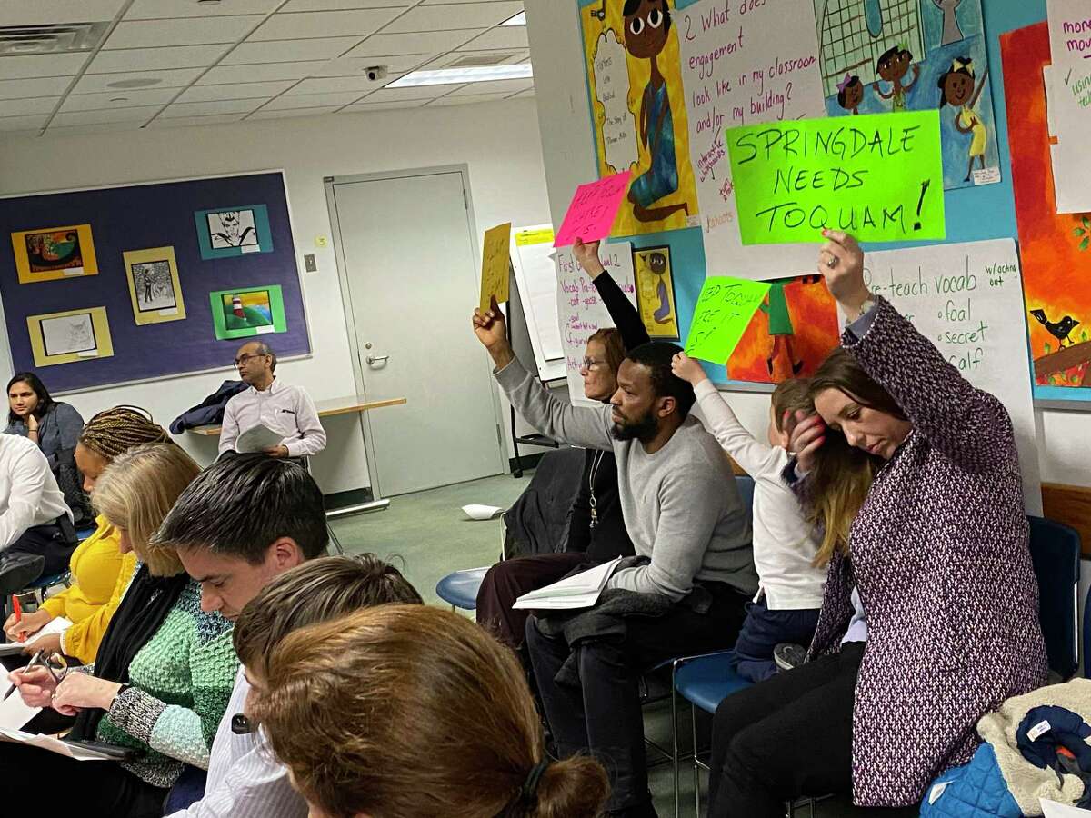 Springdale residents hold up signs protesting the plan to close Toquam Magnet Elementary School at a Stamford Board of Education meeting held on Tuesday, Jan. 28.