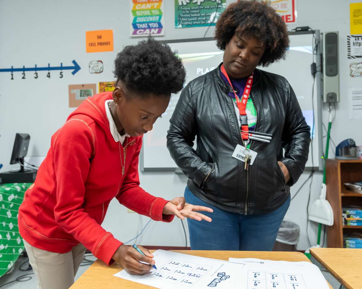 Sixth-grader Janiah Walden, 12, solves a math problem as she plays a game of Tic-Tac-Math with math teacher Courtney Booker. The math department at Willie Ray Smith Magnet Middle School held a STAAR Math night on Wednesday, January 29, 2020 to prepare their scholars for the upcoming STAAR Math test. Fran Ruchalski/The Enterprise