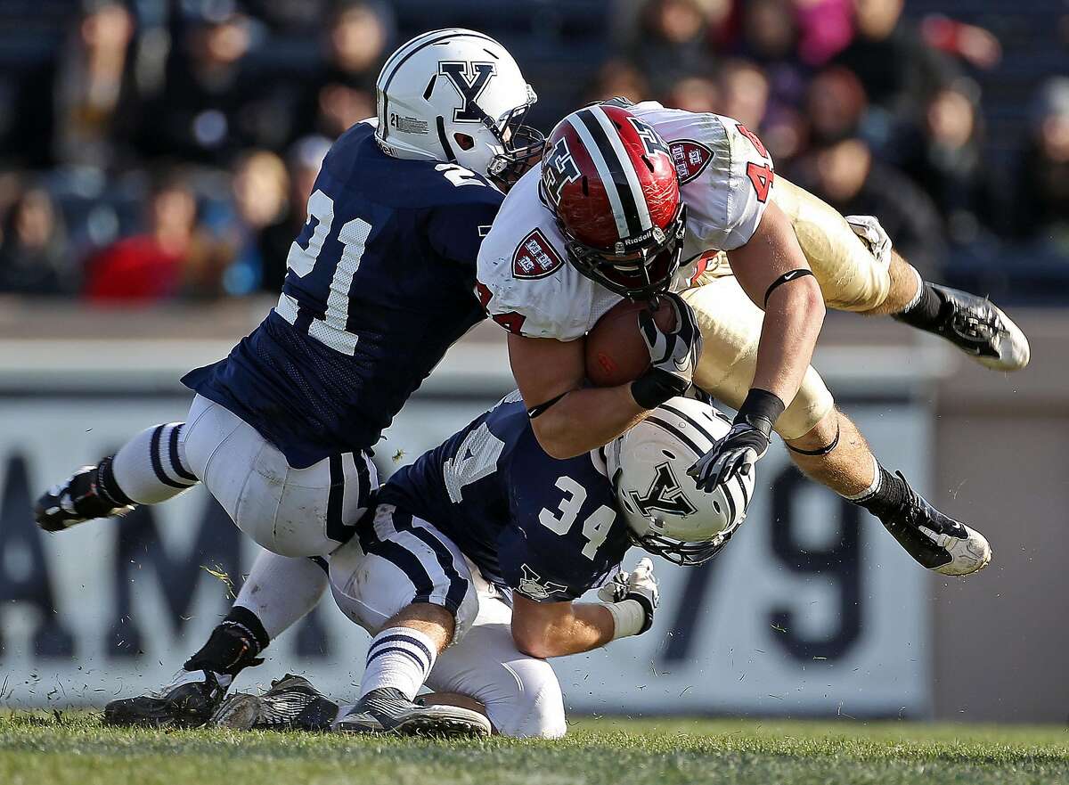 NEW HAVEN - NOVEMBER 19: Harvard tight end Kyle Juszczyk sails for some yardage after a catch, as yale's Collin Bibb (#21) and John Powers (#34) try to bring him down. Yale hosted Harvard in "The Game" at the Yale Bowl. (Photo by Jim Davis/The Boston Globe via Getty Images)