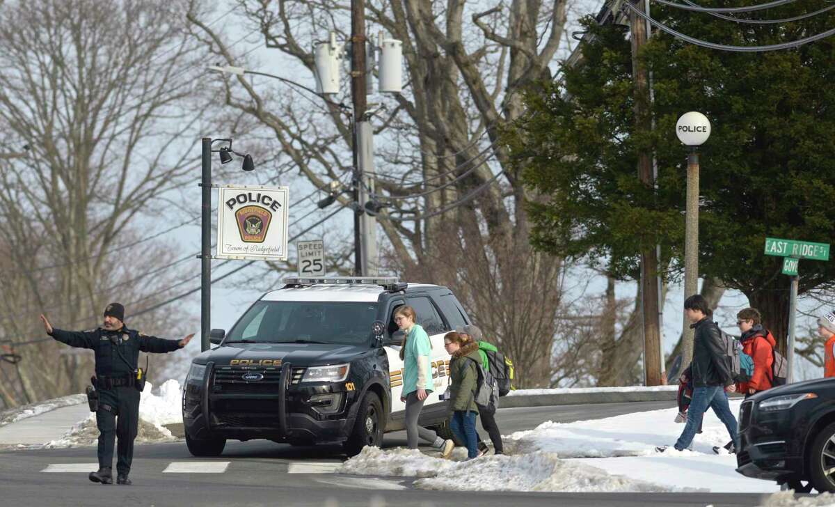 A Ridgefield police officer mans a crosswalk to allow students from East Ridge Middle School to cross in front of the town police station. Thursday, January 23, 2020, in Ridgefield, Conn.