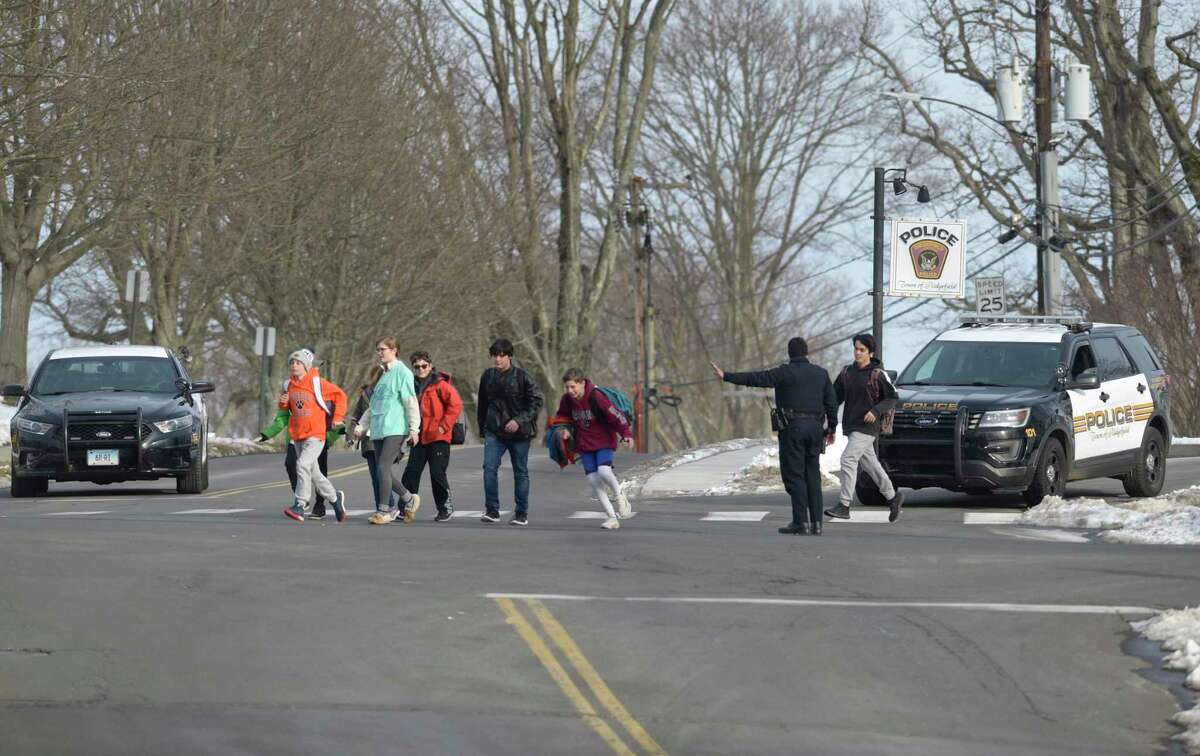A Ridgefield police officer mans a crosswalk to allow students from East Ridge Middle School to cross in front of the town police station. Thursday, January 23, 2020, in Ridgefield, Conn.