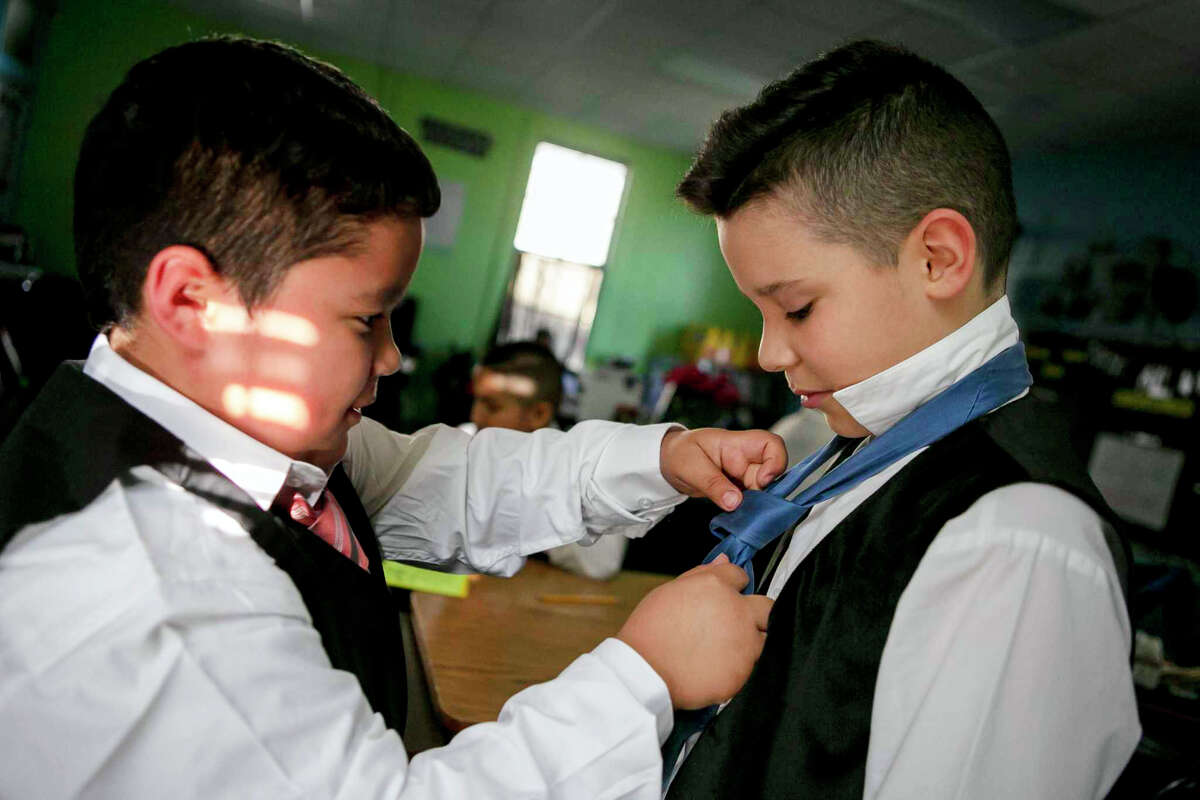 Jordanny Callabero, 9, helps Isaiah Guzman with his tie before an after-school meeting of Caballeros Distinguidos, a boys-only etiquette club, at Briscoe Elementary School . The boys wear dress clothes, practice handshakes and learn table manners and other etiquette rules.