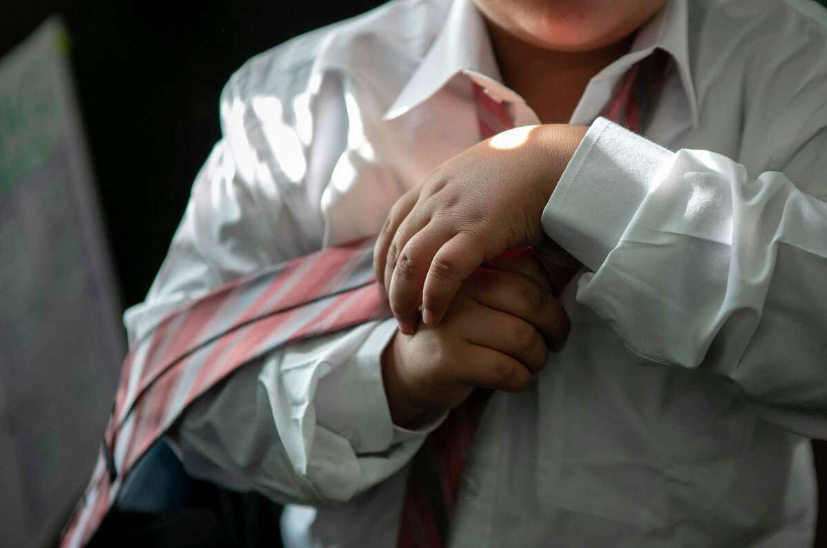Jordanny Callabero, 9, adjusts his tie before an after-school meeting of Caballeros Distinguidos, a boys-only etiquette club at Briscoe Elementary School . The boys wear dress clothes, practice handshakes and learn table manners and other etiquette rules.
